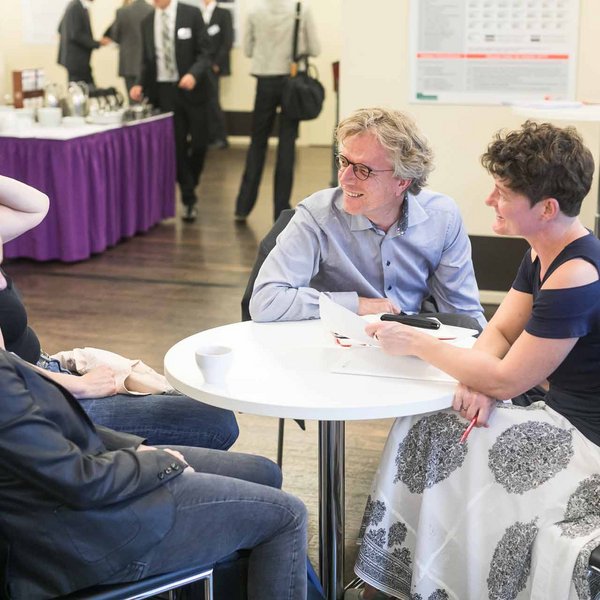 Vier Personen sitzen an einem Tisch, unterhalten sich und lachen.