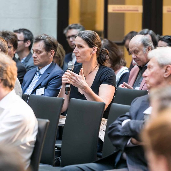 Frau im Publikum spricht in ein Mikrofon.