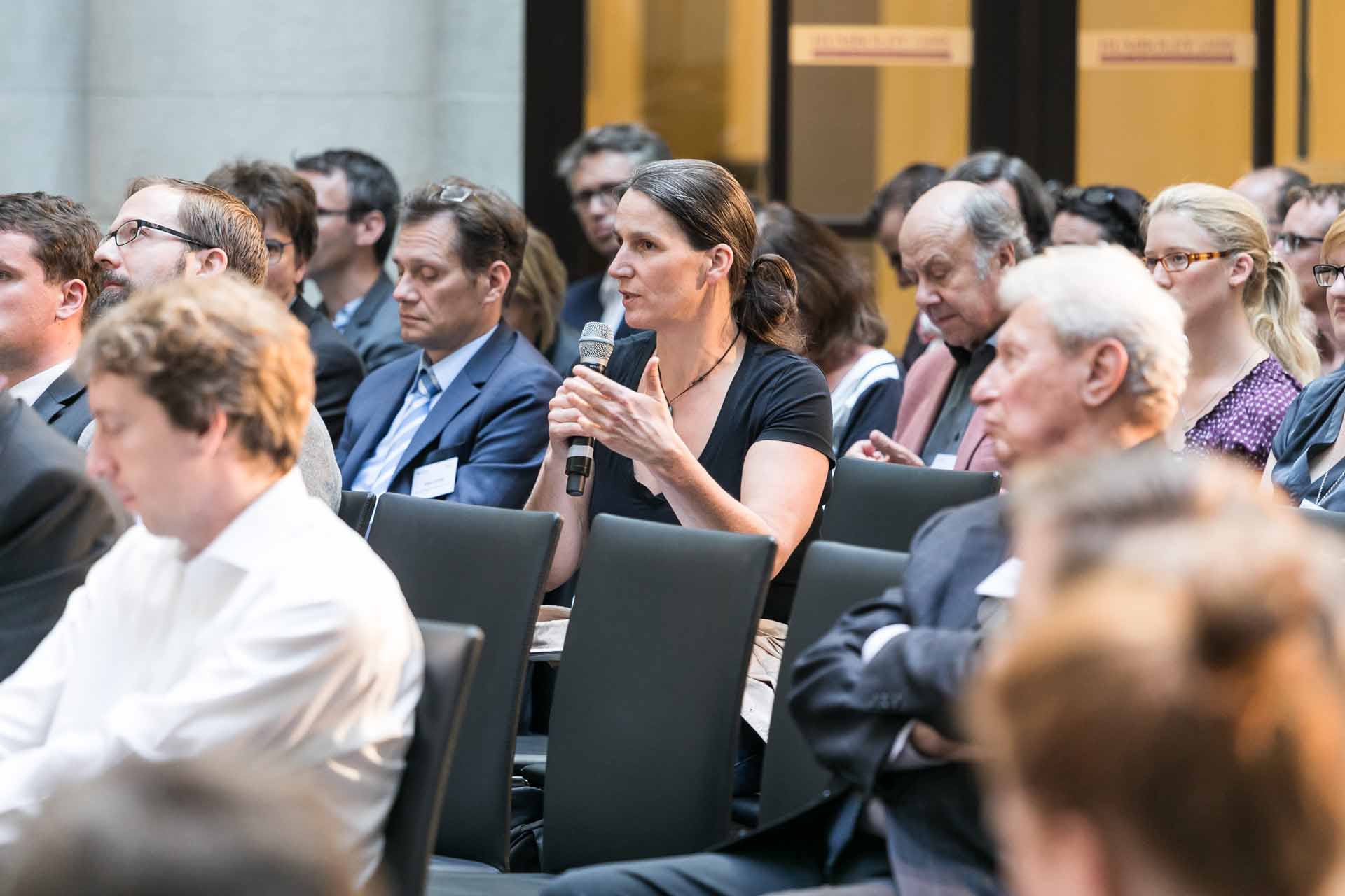 Frau im Publikum spricht in ein Mikrofon.